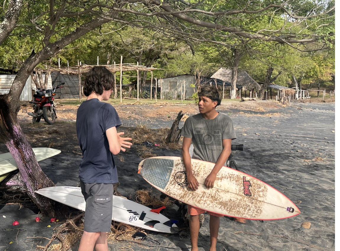 Two young surfers talking on the beach with their boards in Gigante, Nicaragua